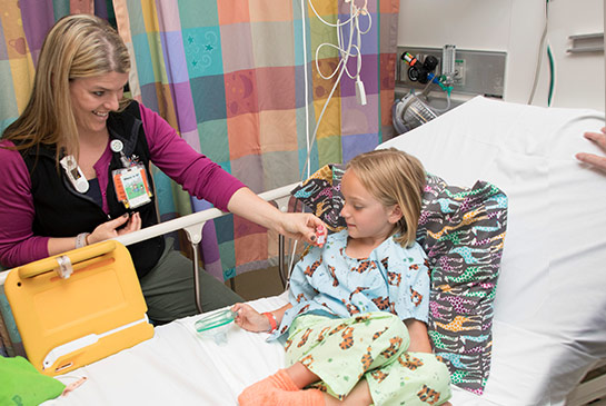 Health care worker assisting child in hospital bed