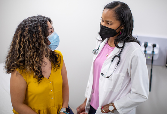 A masked patient talking to a masked health care worker.