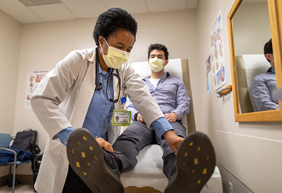 Female physician examining the lower legs of a male patient