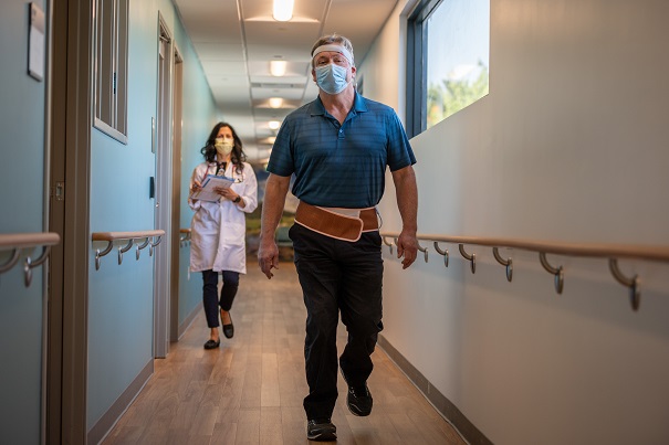 Man walking while physician observes him as part of a respiratory evaluation