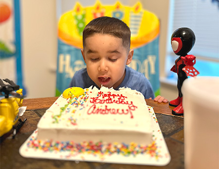 Young boy blows out birthday cake candles
