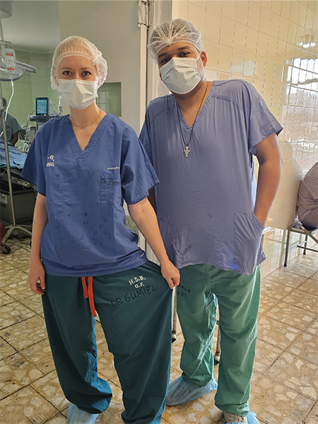 A woman and a man in medical scrubs, masks and hair nets stand at Hospital Santa Bárbara in Sucre, Bolivia