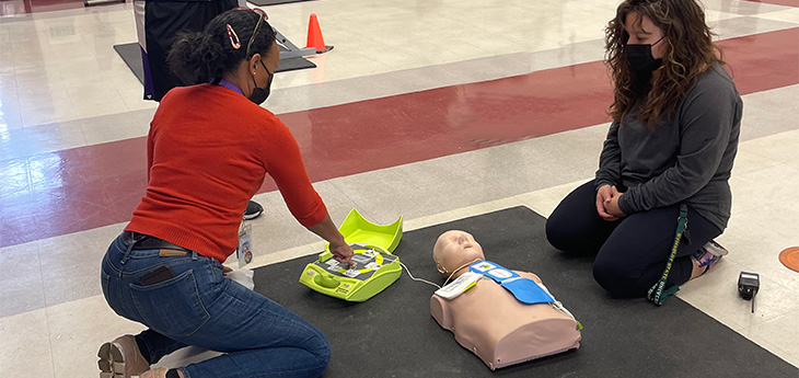 Four people practice CPR on a dummy.   