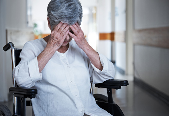 Senior woman in a wheelchair sitting with her hands over her eyes