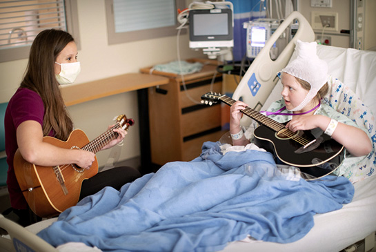 Pediatric Neurology patient plays guitar with doctor who is also playing with patient.