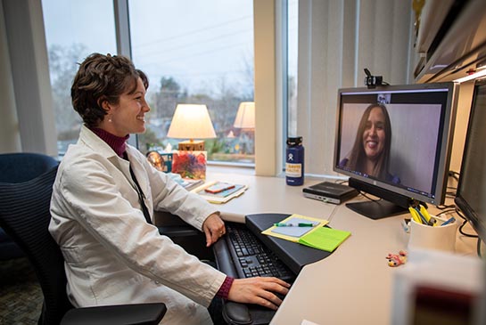 Dr. Crossen using telehealth technology to conference while at her office desk.