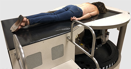 Woman with brown hair lying face down on a scanning machine