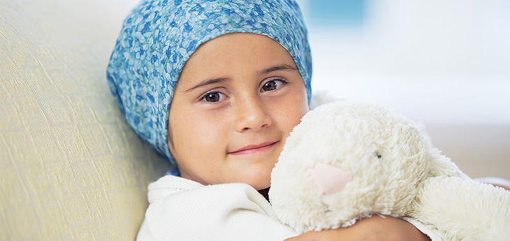 child hugging a stuffed toy in a hospital bed