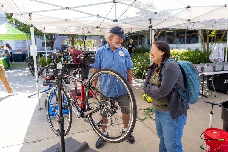 two people talking next to a bike on a bike repair stand